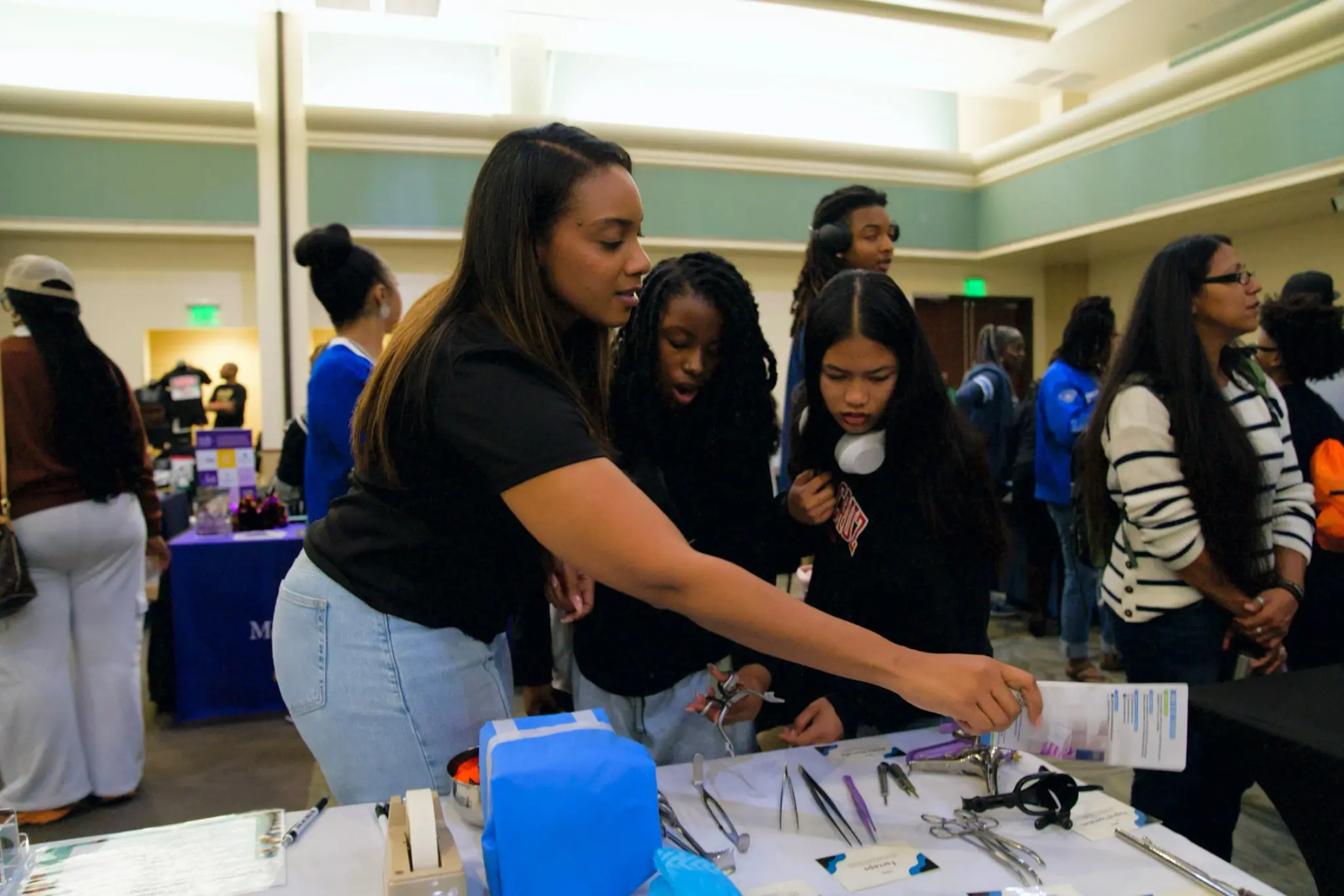 A sterile processing educator introducing young people to surgical instruments during a community career event